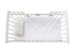 Stylish baby bed with soft pillows and blanket on white background