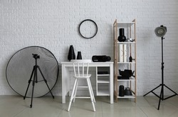 Workplace and shelf unit with different equipment in modern photo studio interior