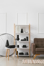 Shelf unit with different modern equipment near light wall in photo studio interior