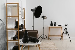 Shelf unit with different modern equipment in light photo studio interior