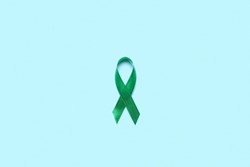 Green ribbon on light blue background, top view. Liver cancer concept