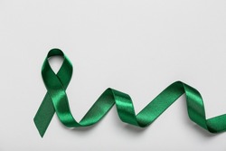 Green ribbon on light background. Liver cancer concept