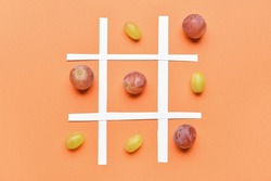 Game of Tic-tac-toe with ripe grapes on color background