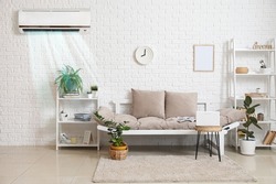 Stylish interior of light living room with sofa, shelf units and air conditioner