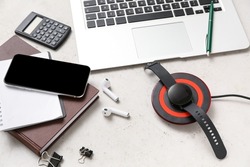 Modern wireless charger pad, different gadgets and notebooks on light background