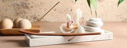 Beautiful spa composition with incense, flower and massage stones on table. Zen concept