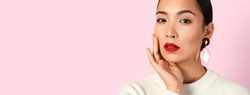 Fashionable young Asian woman on pink background with space for text