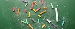 Pieces of colorful chalk on school blackboard, top view