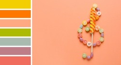 Violin clef  made of sweet candies on beige background. Different color patterns