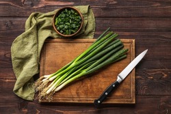 Composition with bunch of fresh green onion and knife on wooden background