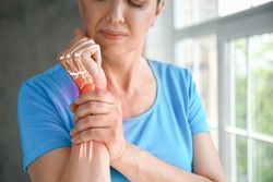 Mature woman having pain in wrist at home