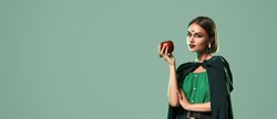 Beautiful woman with apple dressed as witch for Halloween on green background with space for text
