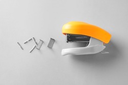 Orange stapler with staples on white background