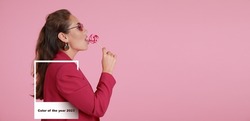 Portrait of fashionable young woman with lollipop on pink background. Viva Magenta - color of new year 2023