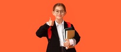 Happy little school girl with books showing thumb-up gesture on orange background