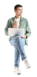 Young guy with cup of coffee and laptop sitting in chair on white background