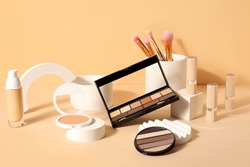 Decorative cosmetics with brushes and podiums on beige background