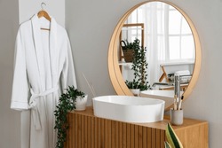 Wooden cabinet with sink bowl, faucet and mirror in interior of bathroom