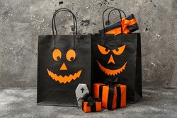 Composition with shopping bags, gift boxes and tasty cookie for Halloween on grunge grey background