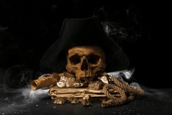 Travel equipment with golden nuggets, human skull, old manuscripts and pirate hat on black background