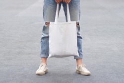 model hold blank white fabric tote bag for save environment on street fashion