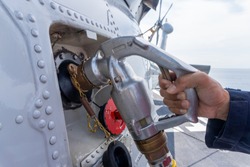 close up of the helicopter refueling  operation onboard the navy ship while the ship is underway at sea