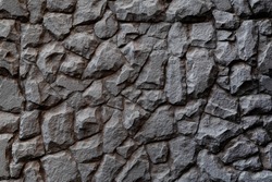 Dark masonry wall texture. Black stones and rocks of different shape, gray background 