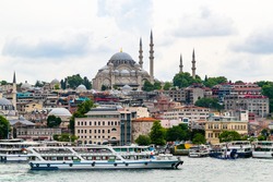 Istanbul cityscape with boats and Suleymaniye Mosque (Ottoman imperial mosque). Old town with colored buildings. Eminonu Ferryboat docks facing the mouth of the Golden Horn Bay.View from Galata bridge