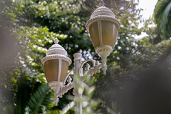 Spherical vintage lantern of two lamps in the garden, hanging iron grate patterned street lamp round shape with white glass, close-up ball-shaped lantern with metal cast elements, garden lightning