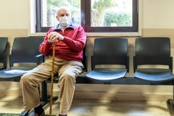 elderly man sitting in doctor's office in a hospital with respirator
