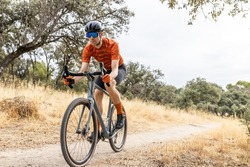 young male cyclist with his gravel bike riding in the countryside, front view