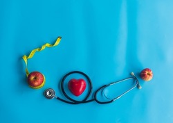 Medical  stethoscope , red  heart  shape  and  yellow  tape  measure  wrapped  around  the  apple  for  the  health  concept . Top  view and  copy  space for  use .