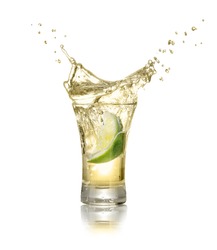 gold tequila shot with splash isolated on white background. Lime is falling in the alcohol drink