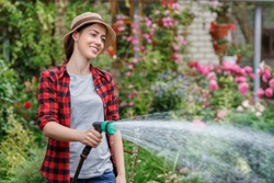 happy young woman gardener watering garden with hose. Hobby concept
