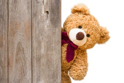 Brown cute teddy bear sneaked behind the old wooden door isolated on white background. Copy space for text and content.