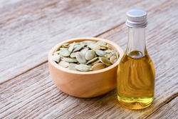 Pumpkin seed oil in glass bottle and dry pumpkin seed isolated on wooden table background.