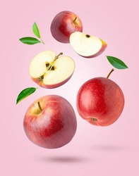 Red apple with green leaf levitate isolated on pink color background.
