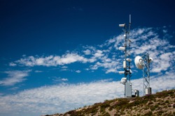 Mountain top weather station with a blue sky and scattered clouds