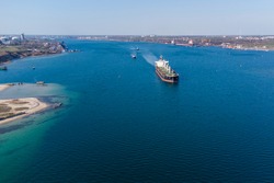 The dry cargo vessel enters the port with the help of tugs. Photo from a helicopter. Bird's-eye view