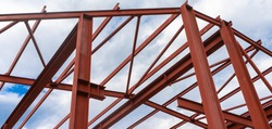 Red metal structure against the sky. Metal frame of a building, hangar or production facility.