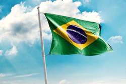 Waving Flag of Brazil in Blue Sky. Brazil Flag on pole for Independence day. The symbol of the state on wavy cotton fabric.