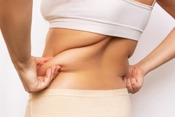 Cropped shot of a young woman holding fat folds on her back isolated on a white background. Overweight, flabby and sagging muscles. Exercises for the back. Body positive