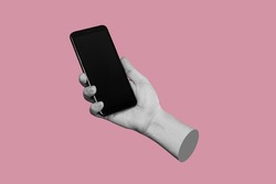 Mobile phone with black screen in female hand isolated on a pink color background. Blank with an empty copy space for the text. Trendy collage in magazine urban style. Contemporary art. Modern design