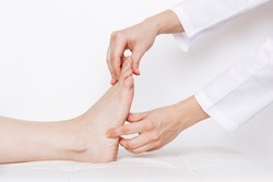 Examination of a young woman by an orthopedist. Cropped shot of female doctor holding a girl's foot in her hands. Flat feet, injury. Foot treatment. Pain from uncomfortable shoes