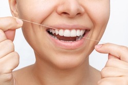 Cropped shot of a young attractive caucasian woman flossing her teeth after meal with dental floss isolated on a white background. Dental health care, oral hygiene, evening routine. Dentistry concept
