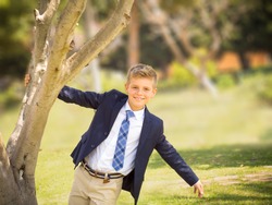 fresh portrait of a boy dressed in a suit and tie in a park for a special event like a communion or wedding