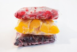 Three packages with frozen fruts on white background, front view.