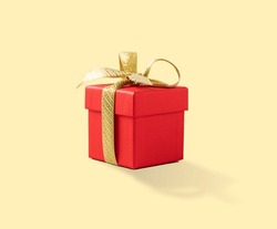 Red present box with gold ribbon on a yellow background. Gift concept for a birthday, wedding or new year. Copy space.