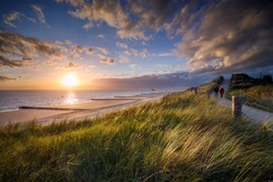 two people walking along the coastal path at sunset at the Zeeland coast near Zoutelande