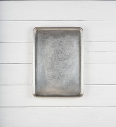 Top View of a Metal Cookie Sheet Cooking Pan Laying or Hung Vertical centered on a Rustic White Gray Wood Board Background with room or space for copy, text, your words or ideas.Planks are horizontal